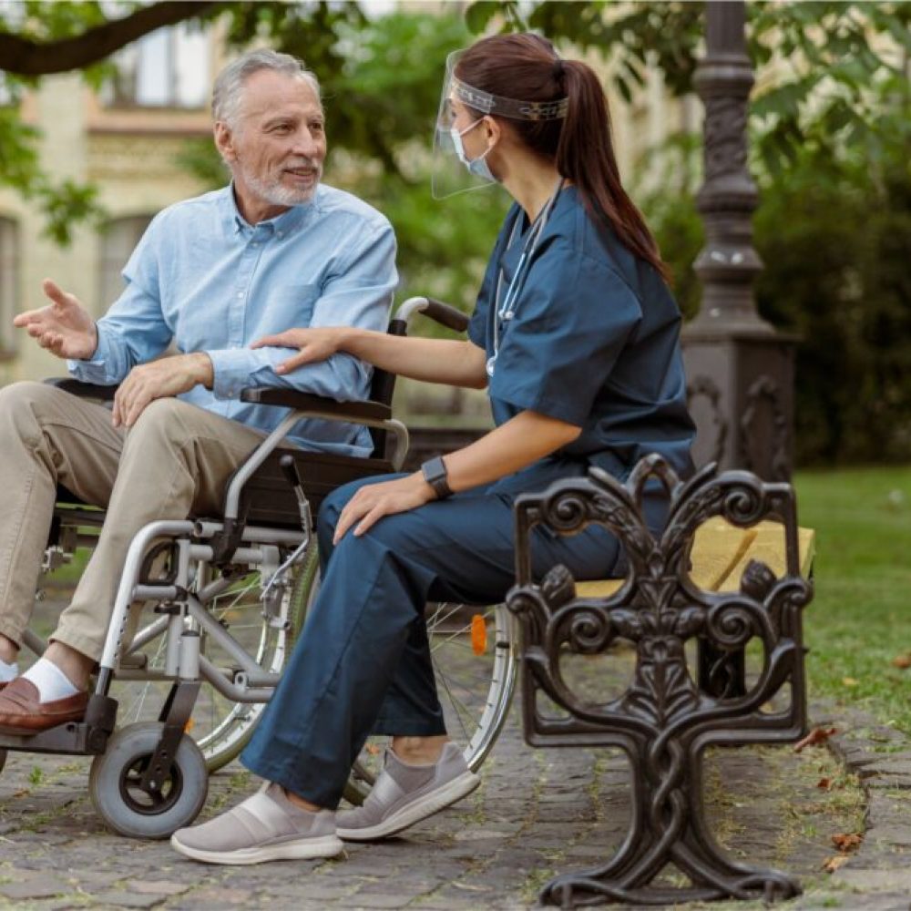 Caregiver assisting a man in wheelchair.